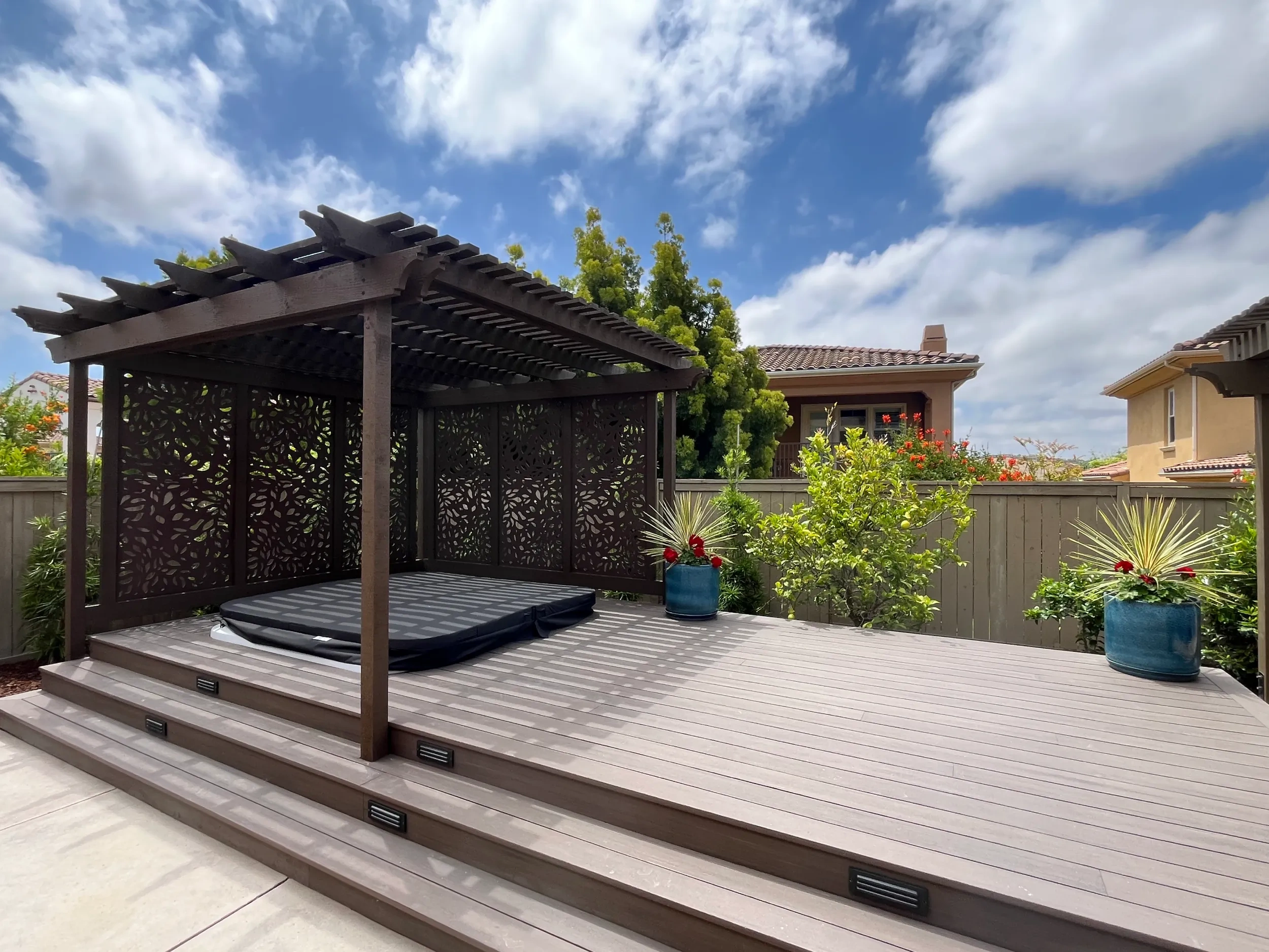 Partially in-ground spa, composite deck, and custom pergola with OutDeco panels in a stylish outdoor retreat.