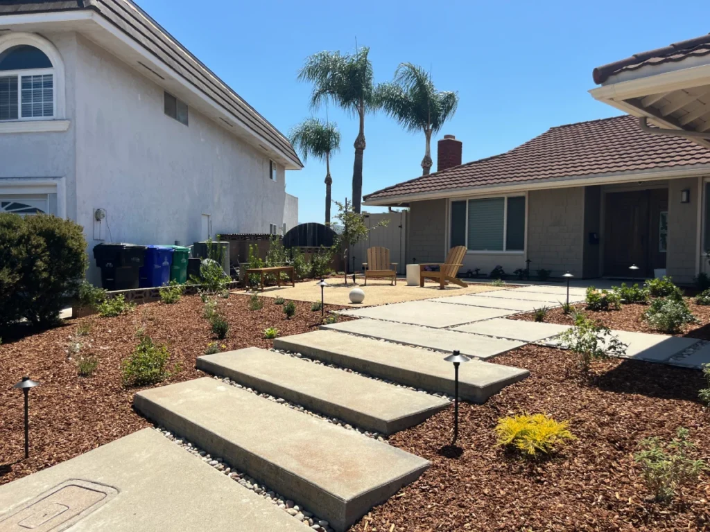 Modern concrete pathway with steppers and beach pebble accents in Rancho Bernardo renovation.