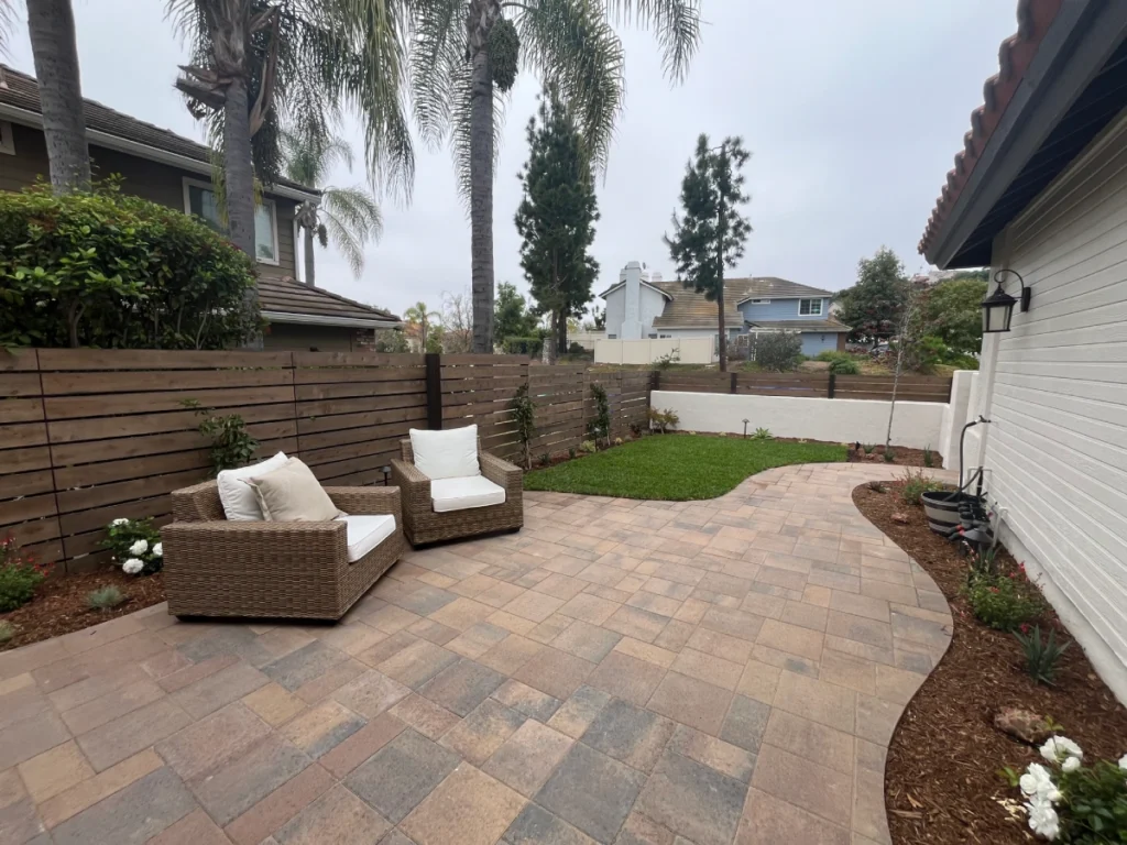 Backyard view of curved paver patio furnished for outdoor living.