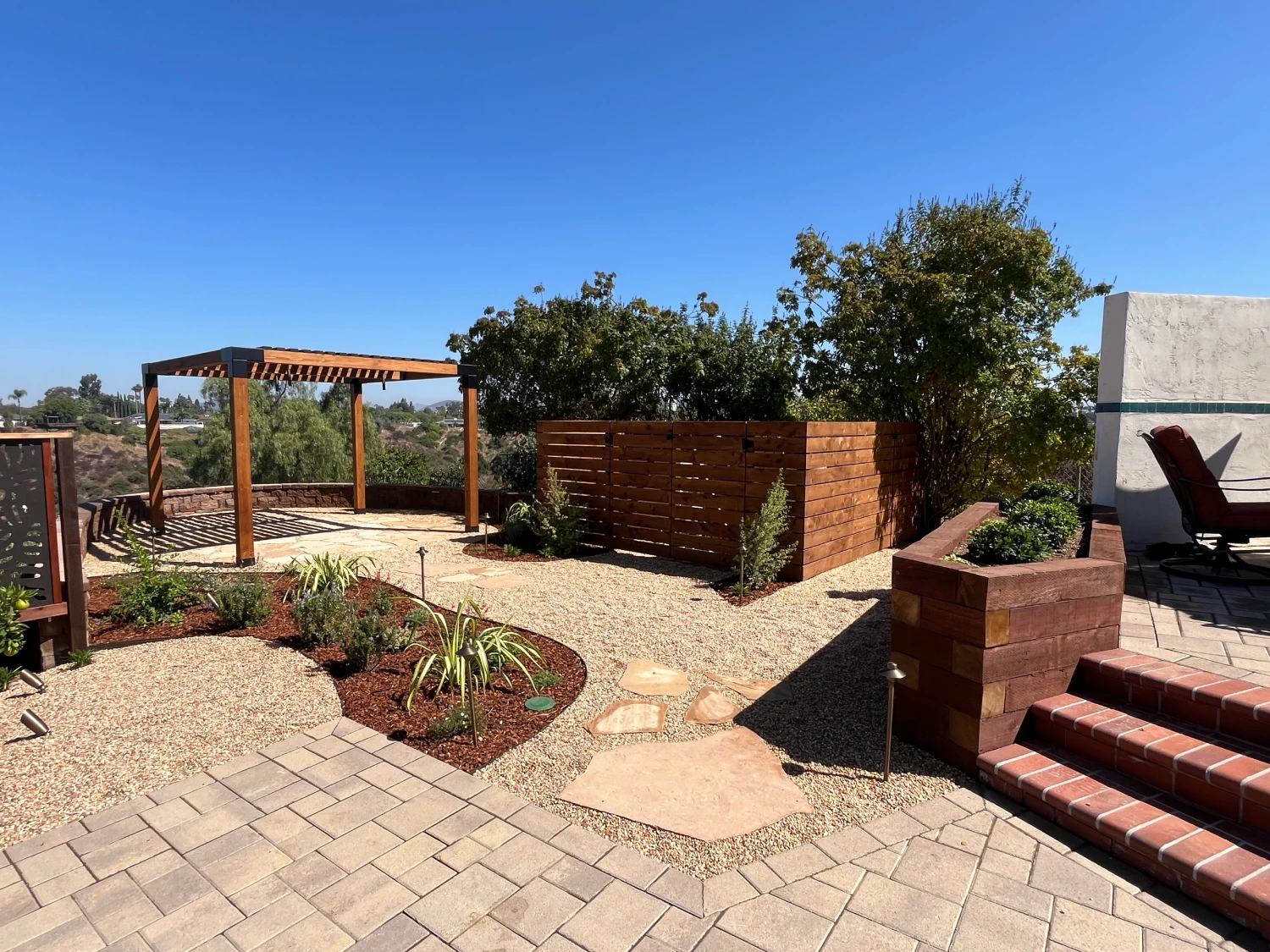 Front view of overhead pergola structure, flagstone pathway, and Mediterranean-style planting in Talmadge Canyon remodel.
