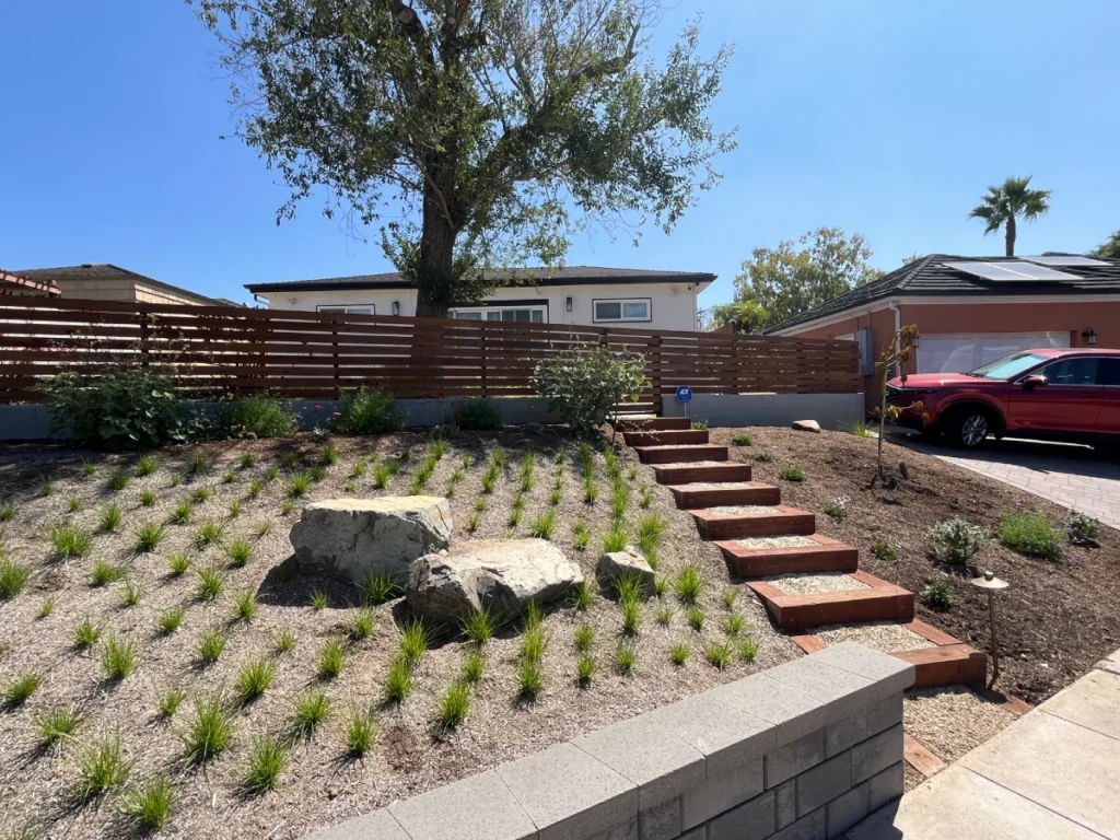 Front view of modular block wall, flagstone, and timber steps in Talmadge landscape remodel.